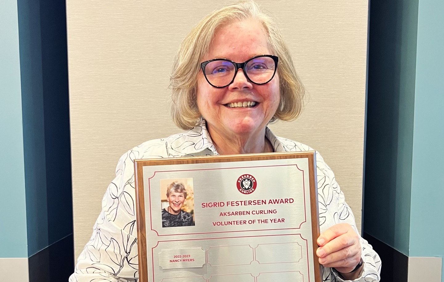 Nancy Myers holding the Sigrid Festersen Volunteer of the Year Award plaque